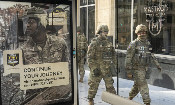 National Guard troops walk past a recruitment sign for the Army National Guard in Washington, on Jan. 19, 2021. (Nathan Howard/Getty Images)