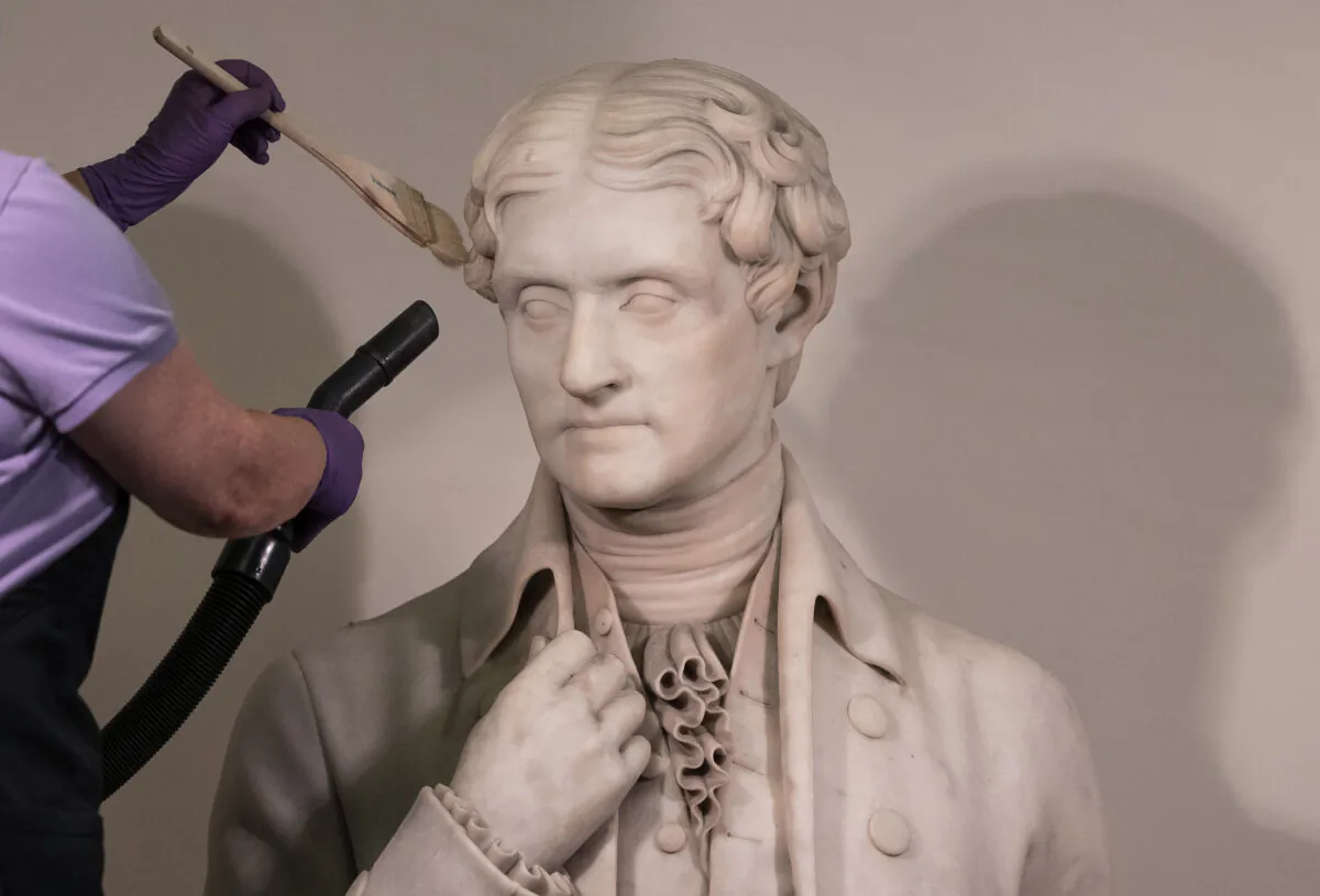 A worker cleans a statue of President Thomas Jefferson inside the Capitol on Aug. 4, 2021. (Kevin Dietsch/Getty Images)