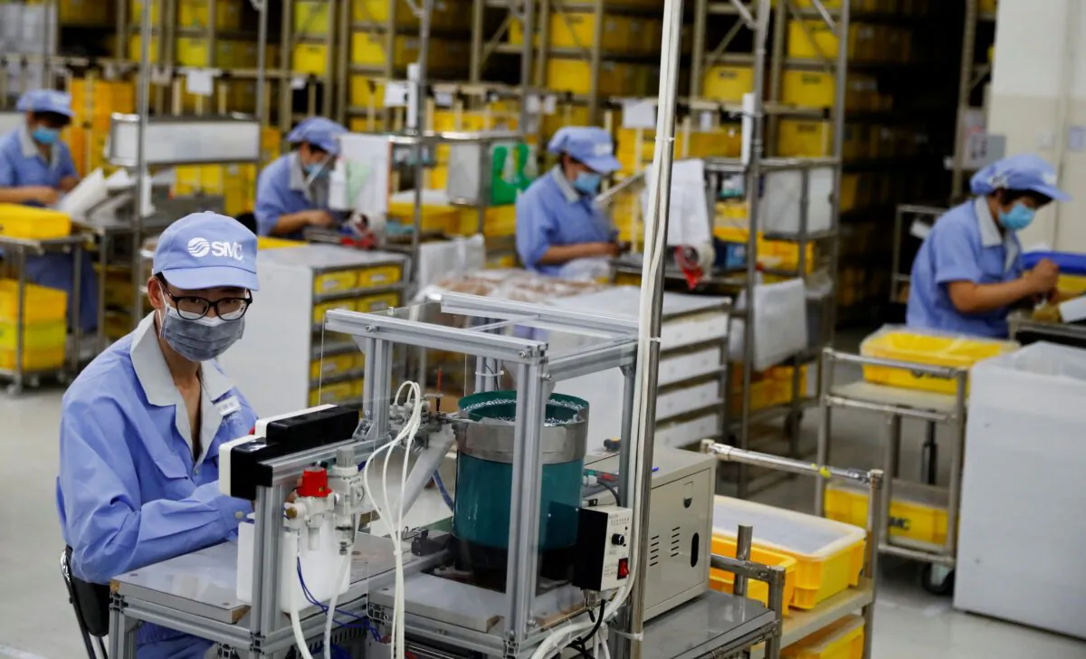 Employees wearing face masks work at a factory of the component maker SMC in Beijing on May 13, 2020. (Thomas Peter/Reuters)