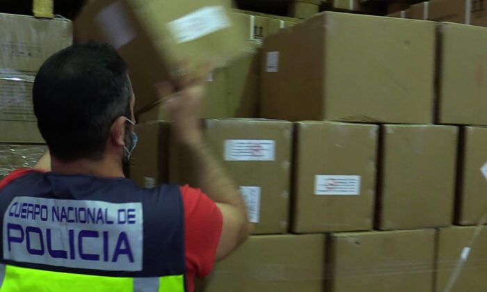 An agent from the Spanish National Police seizes a pallet with COVID-19 antigen tests after an inspection appears police to believe the tests fail to comply with specific protocols set by the government. (Courtesy of Spanish National Police)