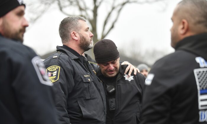 Bradey Police Lt. Philip Trudeau (L) comforts Bourbonnais Police officer Andy Cox following a ceremonial procession for fallen Bradley Police Sgt. Marlene Rittmanic, in Bourbonnais, Ill., on Dec. 30, 2021. (Tiffany Blanchette/The Daily Journal via AP)