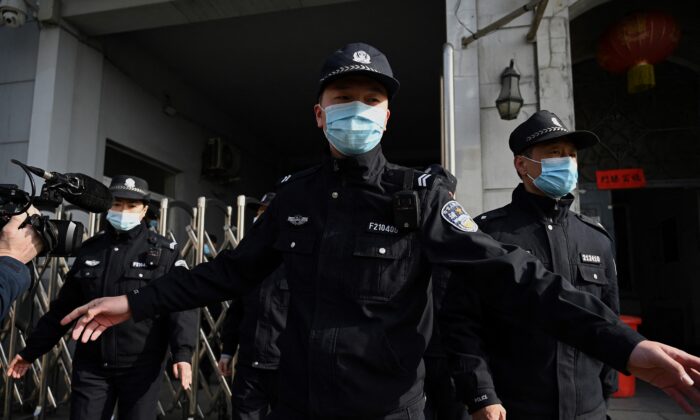 Policemen secure a side entrance following the arrival of police vehicles at the Dandong Intermediate People's Court in China's northeast Liaoning province on March 19, 2021. (Noel Celis/AFP via Getty Images)