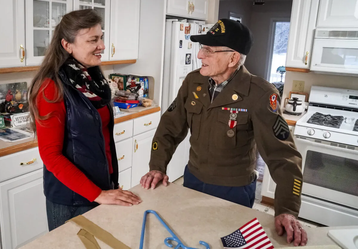 Ernie Rabineau shows off his WW II uniform to Bonnie Koning of the Veterans Esteem Team in Attica, Michigan, on Dec. 21, 2021. (Steven Kovac/Epoch Times)