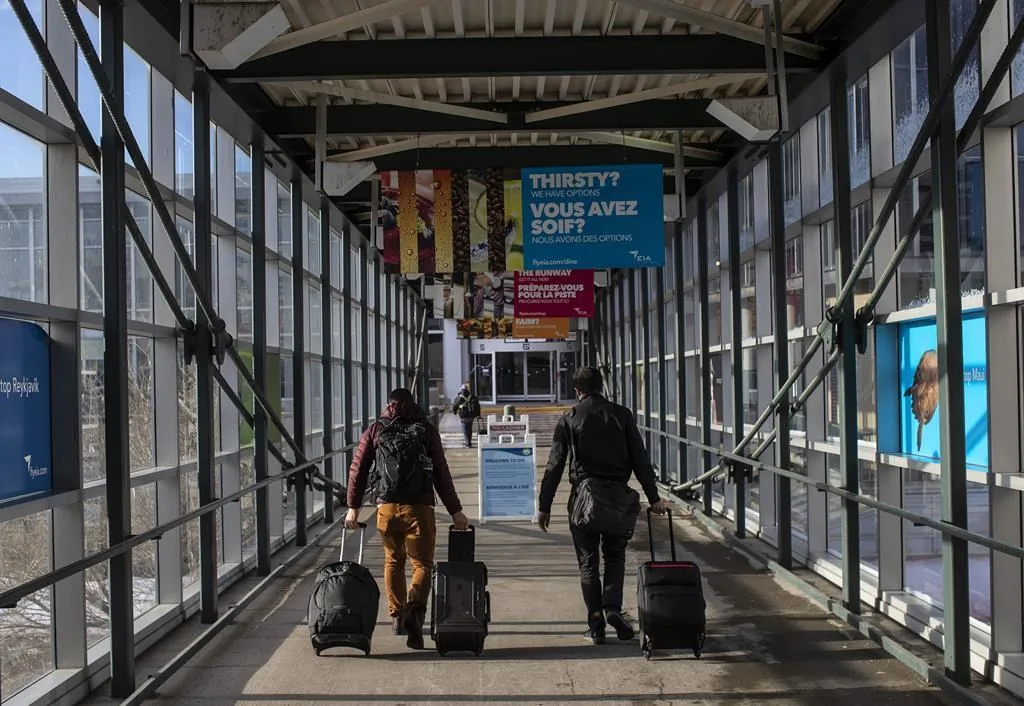 Travelers carry luggage to their flights at the Edmonton International airpot in Edmonton Alta., Dec. 2, 2021. (The Canadian Press/Jason Franson)