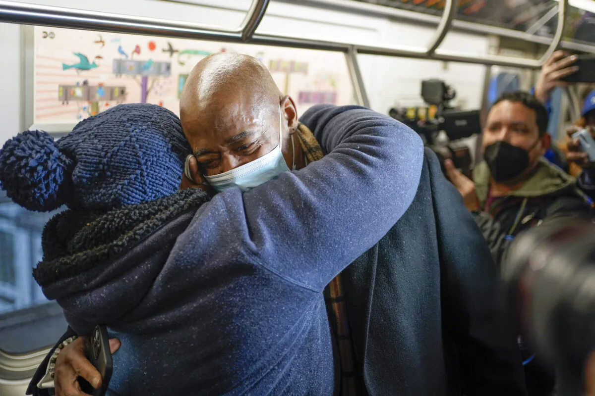 New York City Mayor Eric Adams hugs commuter Pauline Munemya, as he rides the subway to City Hall on his first day in office in New York, on Jan. 1, 2022. (Seth Wenig/AP Photo)