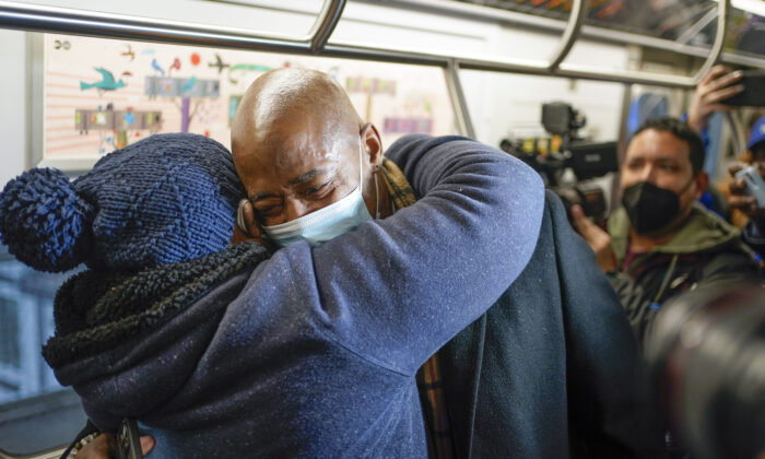 New York City Mayor Eric Adams hugs commuter Pauline Munemya, as he rides the subway to City Hall on his first day in office in New York, on Jan. 1, 2022. (Seth Wenig/AP Photo)