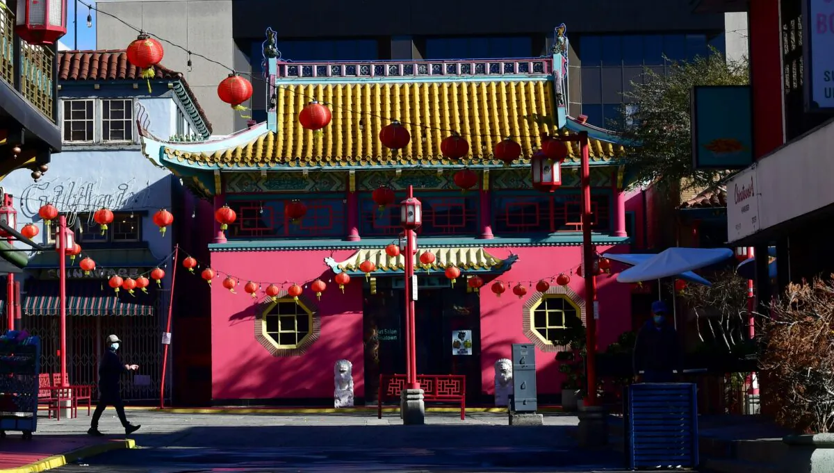 A pedestrian wearing a facemask walks across a deserted Chinatown Central Plaza decorated with red lanterns in Los Angeles on Feb. 12, 2021. (Frederic J. Brown/AFP via Getty Images)