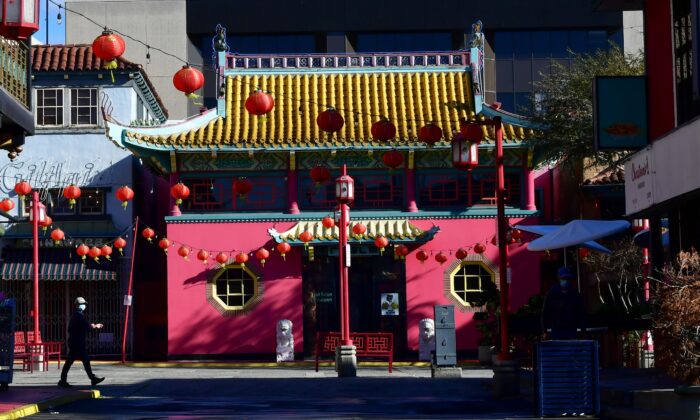 A pedestrian wearing a facemask walks across a deserted Chinatown Central Plaza decorated with red lanterns in Los Angeles on Feb. 12, 2021. (Frederic J. Brown/AFP via Getty Images)