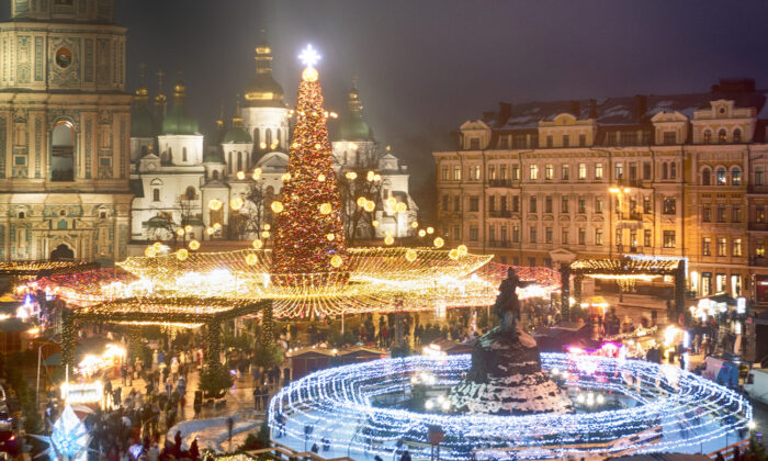 Crowds of people celebrate the New Year around the Christmas tree with the St. Sofia Cathedral in the background in Kyiv, Ukraine, on Dec. 31, 2021. (Efrem Lukatsky/AP Photo)