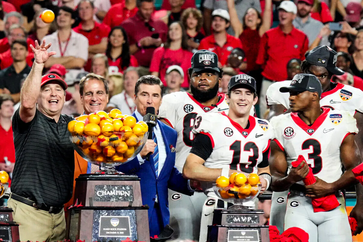 Stetson Bennett #13 and Head Coach Kirby Smart of the Georgia Bulldogs throw oranges from the Orange Bowl trophy to teammates after the Georgia Bulldogs defeated the Michigan Wolverines 36–11 in the Capital One Orange Bowl for the College Football Playoff semifinal game at Hard Rock Stadium, Miami Gardens, Fla., on Dec. 31, 2021. (Mark Brown/Getty Images)