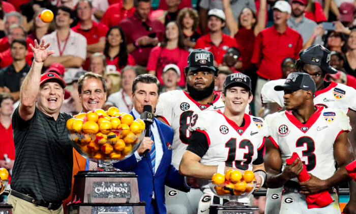Stetson Bennett #13 and Head Coach Kirby Smart of the Georgia Bulldogs throw oranges from the Orange Bowl trophy to teammates after the Georgia Bulldogs defeated the Michigan Wolverines 36–11 in the Capital One Orange Bowl for the College Football Playoff semifinal game at Hard Rock Stadium, Miami Gardens, Fla., on Dec. 31, 2021. (Mark Brown/Getty Images)