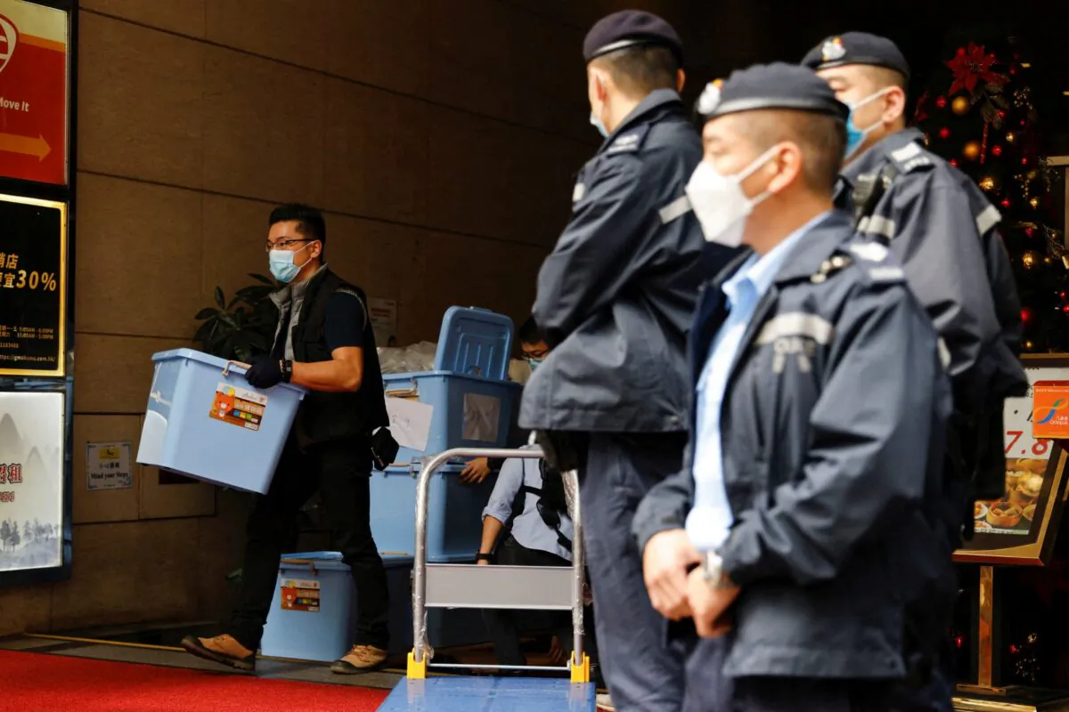 A police officer collects a box of evidence after a search at the office of Stand News in Hong Kong, on Dec.  29, 2021. (Tyrone Siu/Reuters)