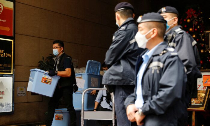 A police officer collects a box of evidence after a search at the office of Stand News in Hong Kong, on Dec.  29, 2021. (Tyrone Siu/Reuters)