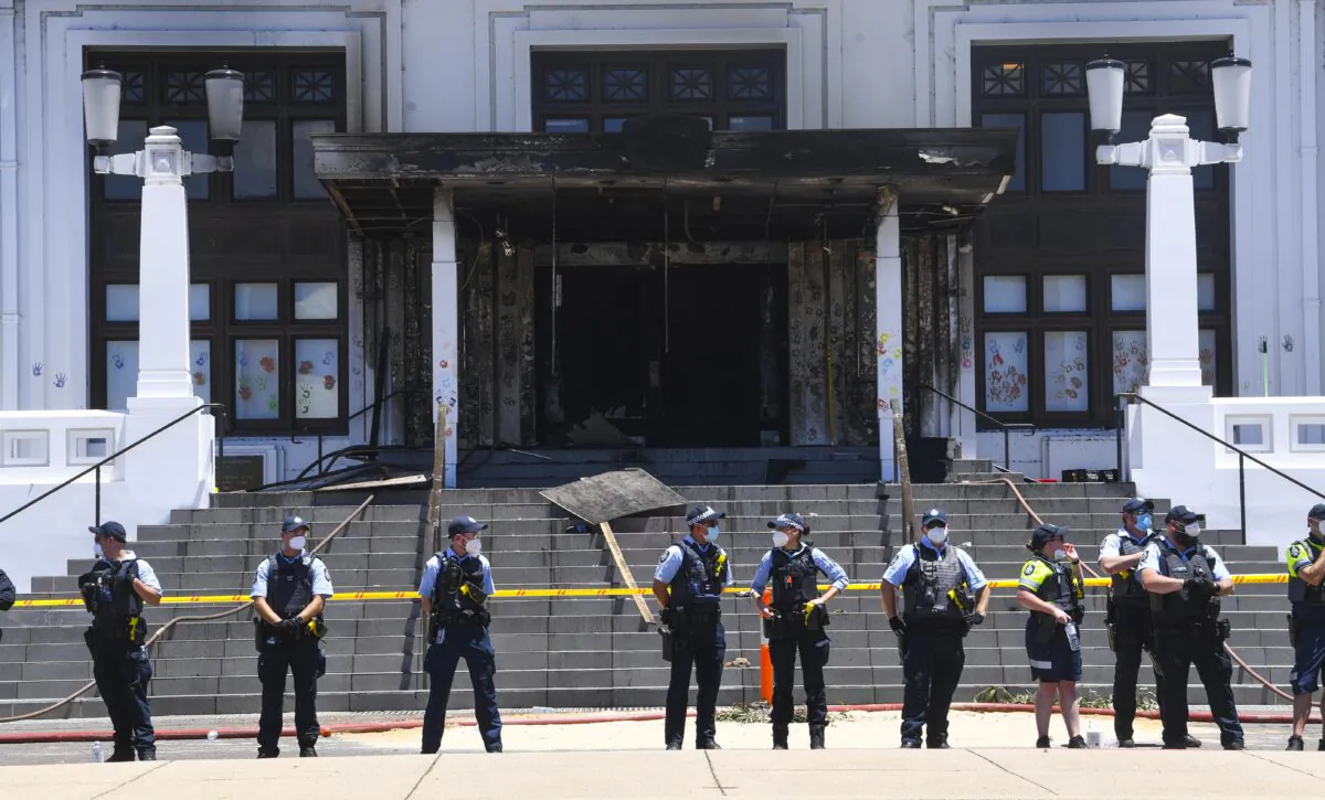 Police officers stand guard outside the fire damaged entrance to Old Parliament House in Canberra, Australia, on Dec. 30, 2021. (AAP Image/Lukas Coch) 