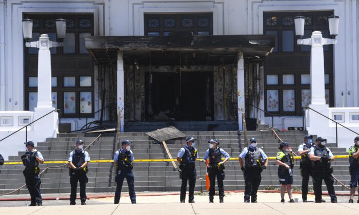 Police officers stand guard outside the fire damaged entrance to Old Parliament House in Canberra, Australia, on Dec. 30, 2021. (AAP Image/Lukas Coch) 