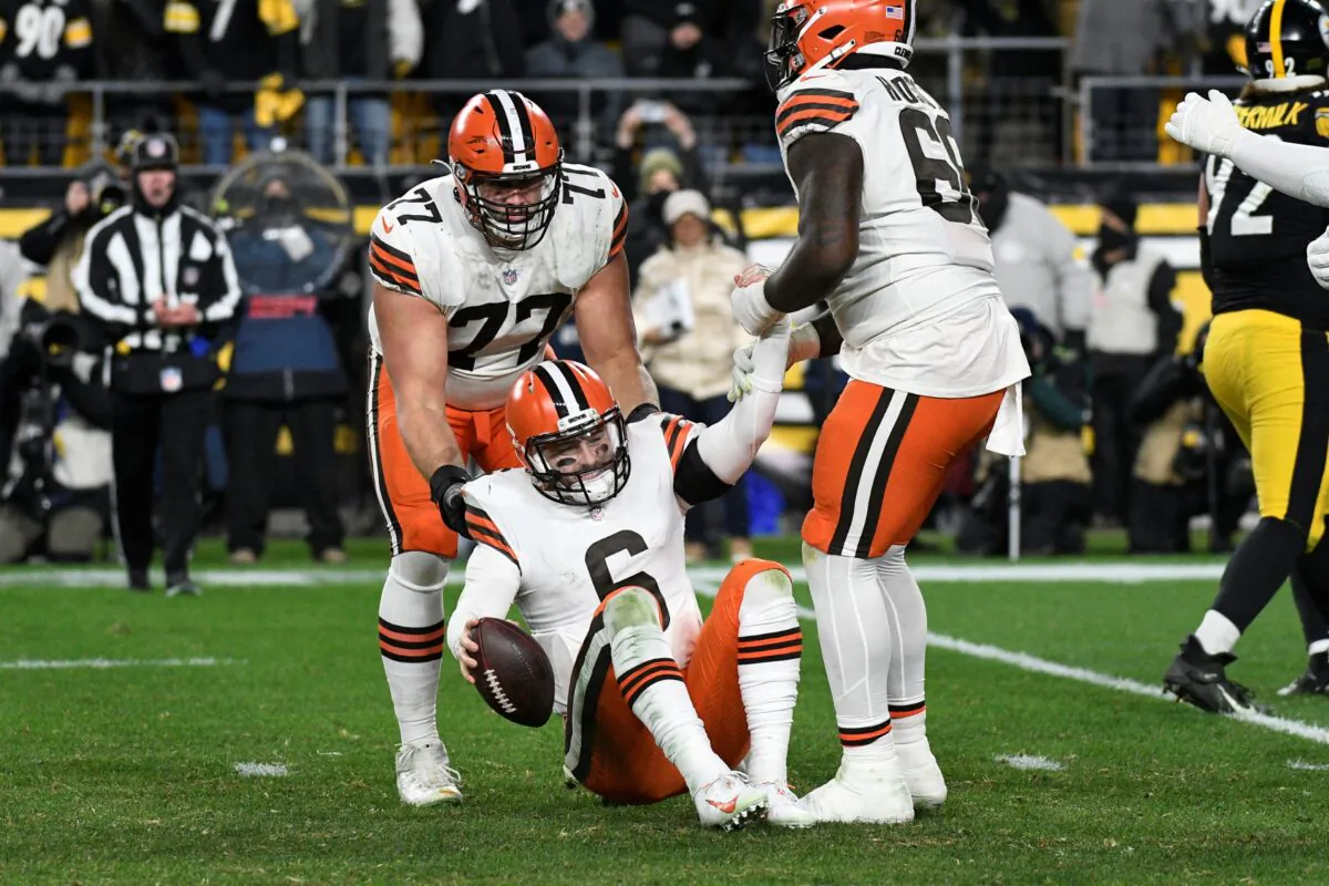 Cleveland Browns guard Wyatt Teller (77) and offensive tackle James Hudson (66) pick up quarterback Baker Mayfield (6) after Mayfield was sacked by the Pittsburgh Steelers during the second half an NFL football game in Pittsburgh on Jan. 3, 2022. (Don Wright/AP Photo)