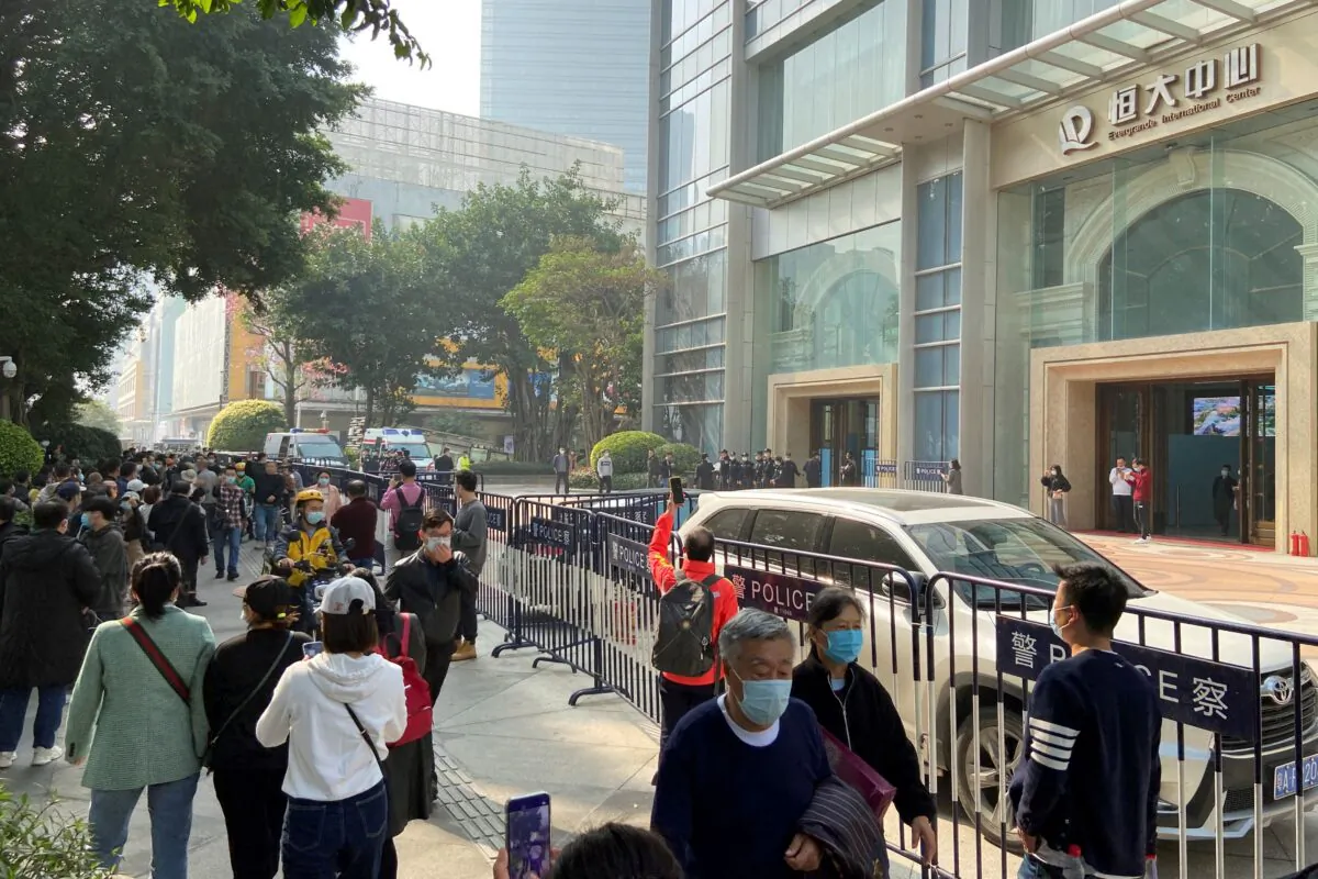 Protesters seeking payment from China Evergrande Group gather as police officers stand guard outside the Evergrande International Center in Guangzhou, Guangdong Province, China, on Jan. 4, 2022. (David Kirton/Reuters)