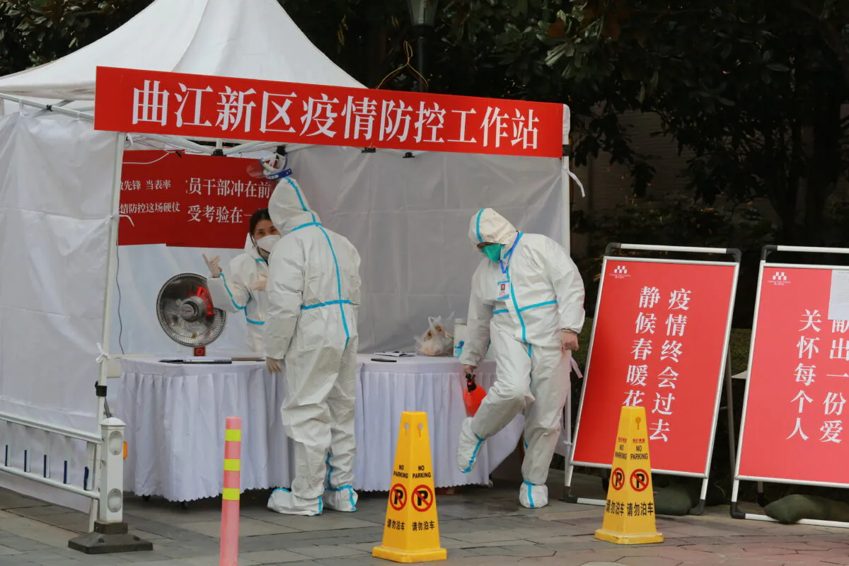 Government workers in protective clothing gather at a work station for pandemic control outside a residential block in Xi'an city in northwest China's Shaanxi Province, on Jan. 3, 2022. (Chinatopix Via AP)