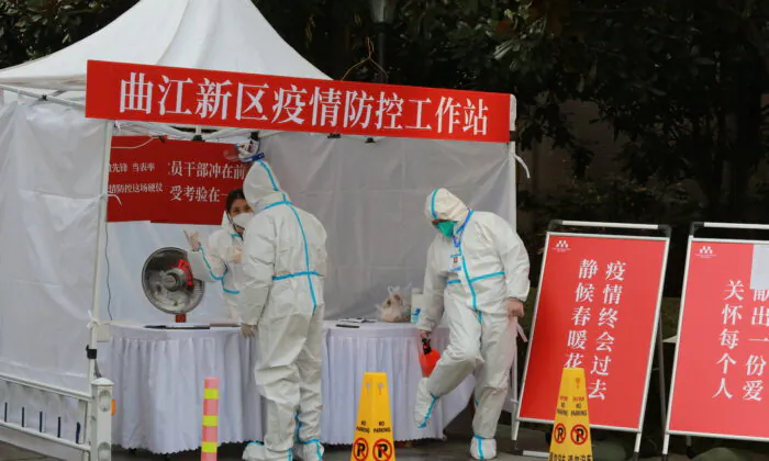 Government workers in protective clothing gather at a work station for pandemic control outside a residential block in Xi'an city in northwest China's Shaanxi Province, on Jan. 3, 2022. (Chinatopix Via AP)