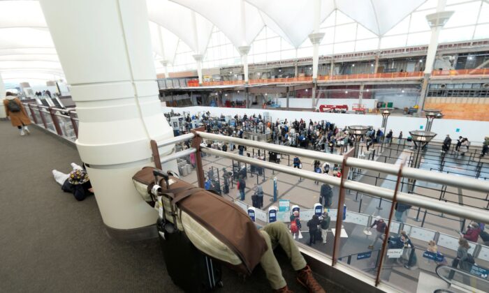 A passenger sleeps amid baggage above the north security checkpoint in the main terminal of Denver International Airport in Denver, on Jan. 3, 2022. (David Zalubowski/AP Photo)