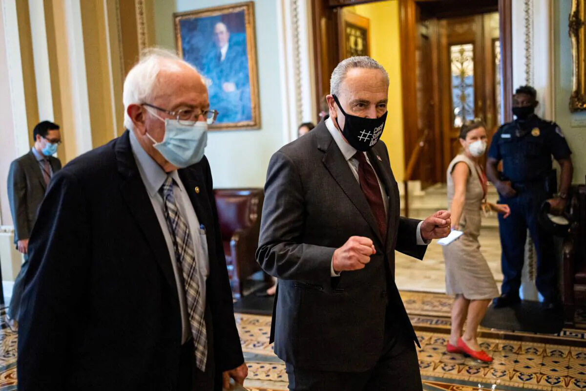Sen. Bernie Sanders (L) (I-Vt.) walks with Senate Majority Leader Chuck Schumer (D-N.Y.) on Aug. 11, 2021, after meeting on a $3.5 trillion budget that was rammed through by Senate Democrats on Aug. 9 in Washington. (Win McNamee/Getty Images)