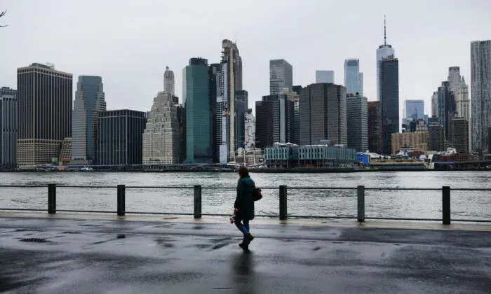 A person walks in Brooklyn while lower Manhattan looms in the background in New York City on March 28, 2020. (Spencer Platt/Getty Images)
