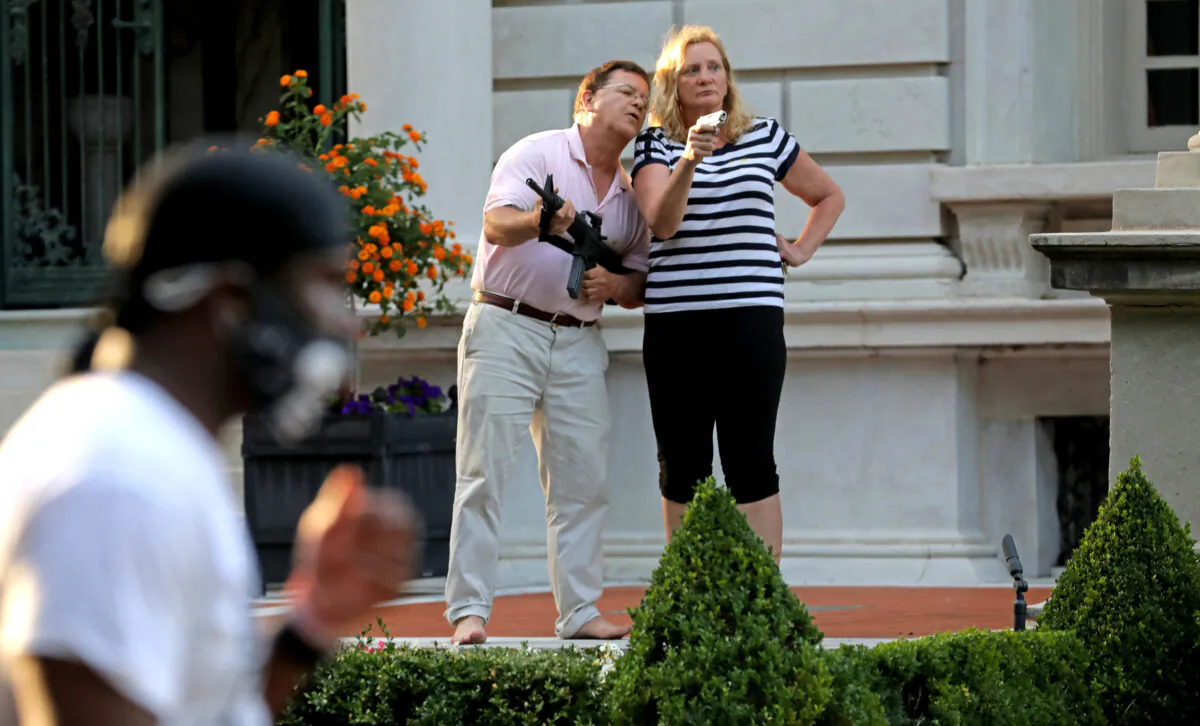 Armed homeowners Mark and Patricia McCloskey, stand in front their house confronting protesters marching to St. Louis Mayor Lyda Krewson's house in the Central West End of St. Louis on June 28, 2020. (Laurie Skrivan/St. Louis Post-Dispatch via AP)