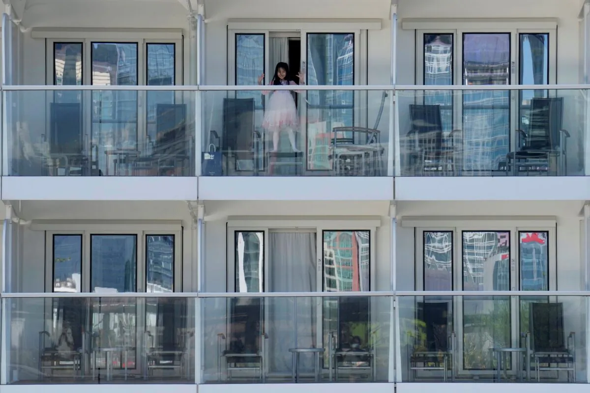A passenger waves from the Spectrum of the Seas cruise ship docked at Kai Tak cruise terminal in Hong Kong on Jan. 5, 2022. (Vincent Yu/AP Photo)