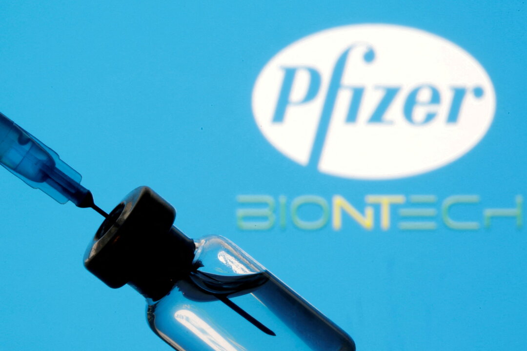 A vial and syringe are seen in front of the Pfizer and BioNTech logos in a file photo. (Dado Ruvic/Reuters)