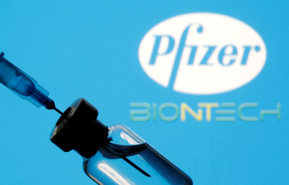 A vial and sryinge are seen in front of a displayed Pfizer and Biontech logo in this file illustration photograph. (Dado Ruvic/Reuters)