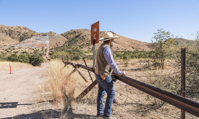 Detective Jake Kartchner with the Cochise County Sheriff’s Office border unit, stands at the U.S.–Mexico border fence that was slated to be replaced with a 30-foot fence before President Joe Biden halted all border wall construction in January 2021, in Cochise County, Ariz., on Dec. 6, 2021. (Charlotte Cuthbertson/The Epoch Times)