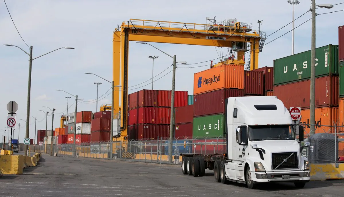 A truck moves past stacked shipping containers at the Port of Montreal in Montreal, Quebec, Canada, on May 17, 2021. (Christinne Muschi/Reuters)