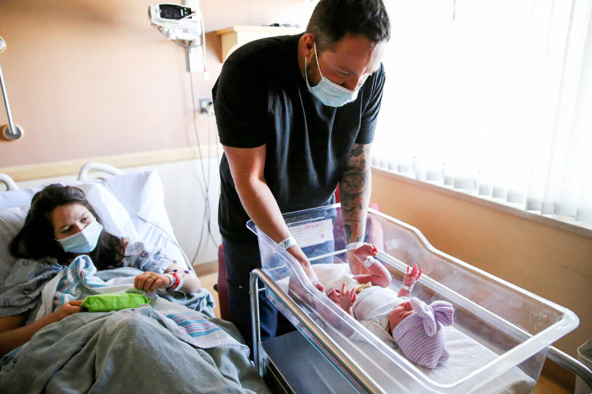 Matthew Carnes prepares to change diapers for his newborn daughter Evelina Carnes as his wife Breanna Llamas keeps watch in the postpartum unit at Providence St. Mary Medical Center in Apple Valley, Calif., on March 30, 2021. (Mario Tama/Getty Images)