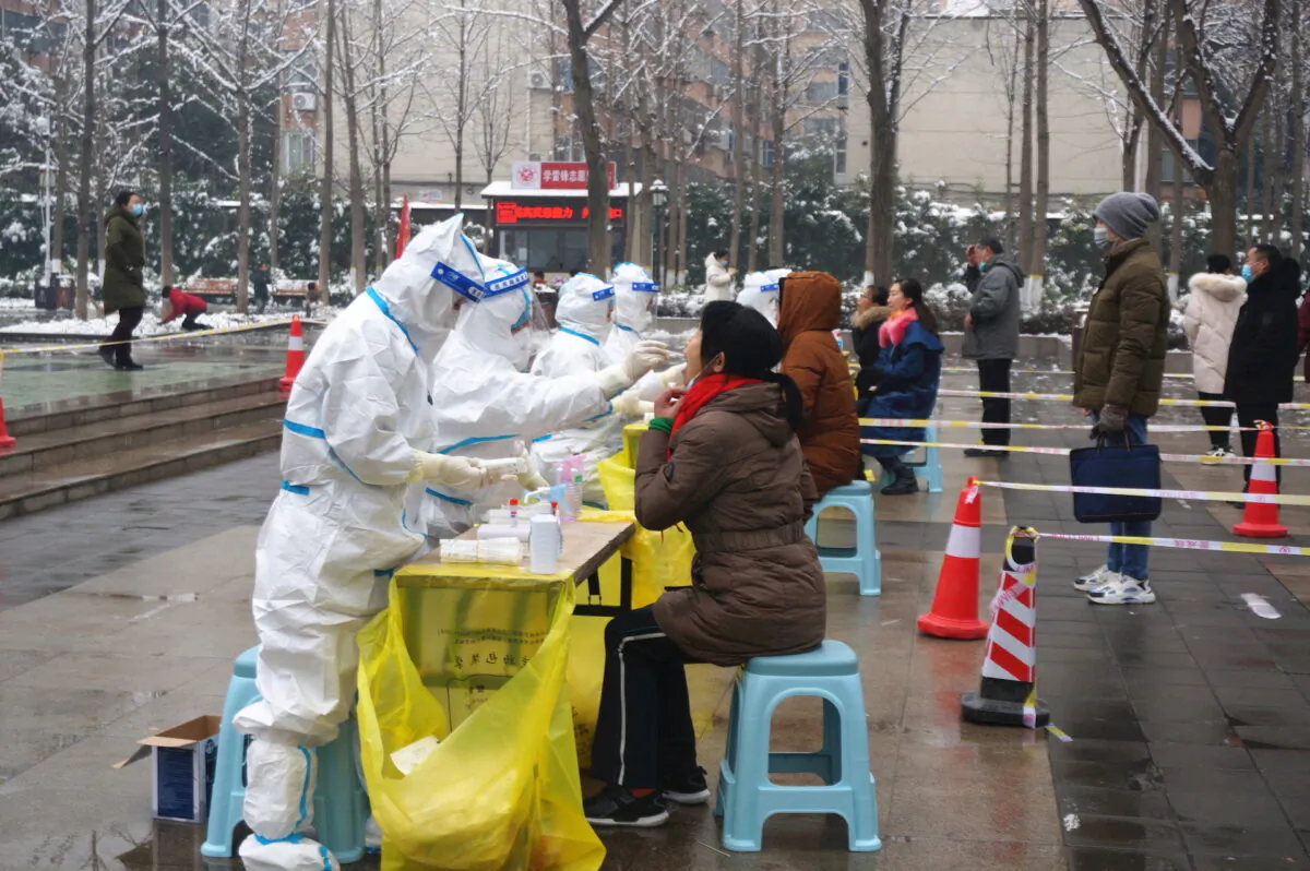 Medical workers in protective suits collect swabs from residents during a citywide nucleic acid testing following cases of the coronavirus disease (COVID-19) in Zhengzhou, Henan Orovince, China, on Jan. 5, 2022. (cnsphoto via Reuters)