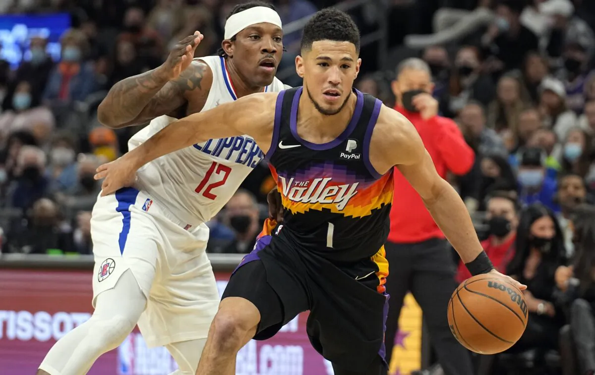 Phoenix Suns guard Devin Booker (1) drives past Los Angeles Clippers guard Eric Bledsoe, during an NBA game in Phoenix on Jan. 6, 2022. (Rick Scuteri/AP Photo)