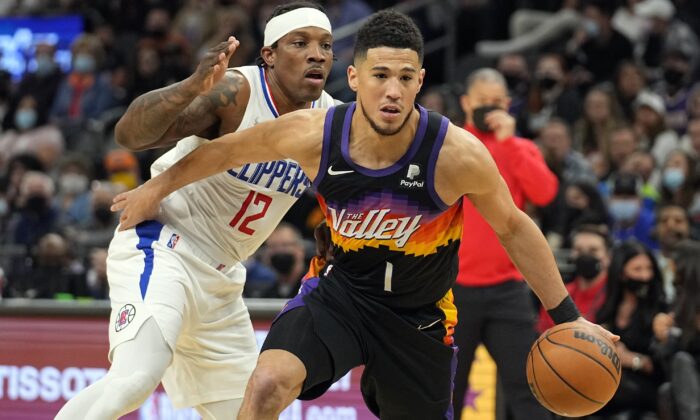 Phoenix Suns guard Devin Booker (1) drives past Los Angeles Clippers guard Eric Bledsoe, during an NBA game in Phoenix on Jan. 6, 2022. (Rick Scuteri/AP Photo)