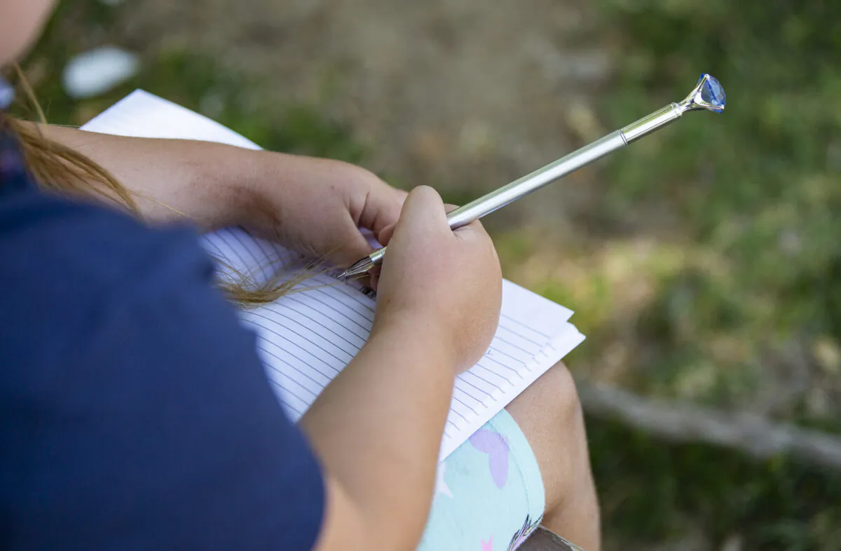 An elementary school student writes on her notebook in Brea, Calif. on May 24, 2021. (John Fredricks/The Epoch Times)