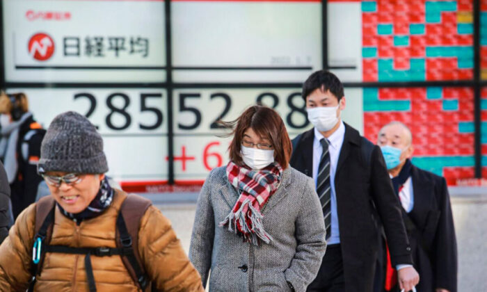 People walk by an electronic stock board of a securities firm in Tokyo, on Jan. 7, 2022. (Koji Sasahara/AP Photo)