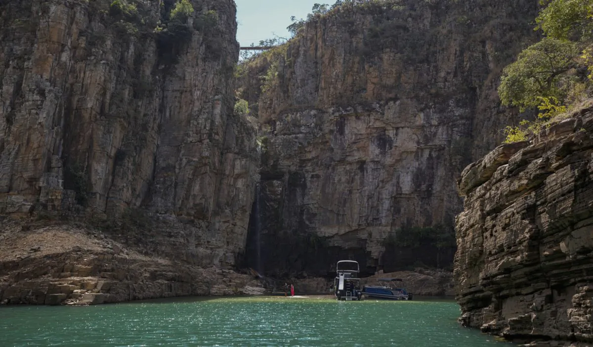 A tourist boat navigates through a canyon in Furnas Lake, near Capitolio City in Brazil on Sept. 2, 2021. (Andre Penner/AP Photo)