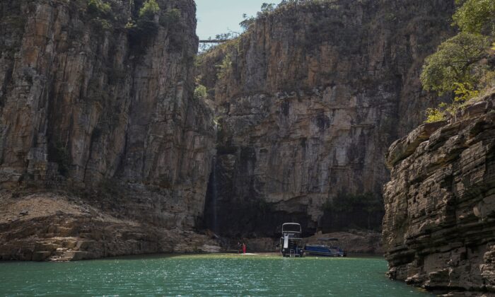 A tourist boat navigates through a canyon in Furnas Lake, near Capitolio City in Brazil on Sept. 2, 2021. (Andre Penner/AP Photo)