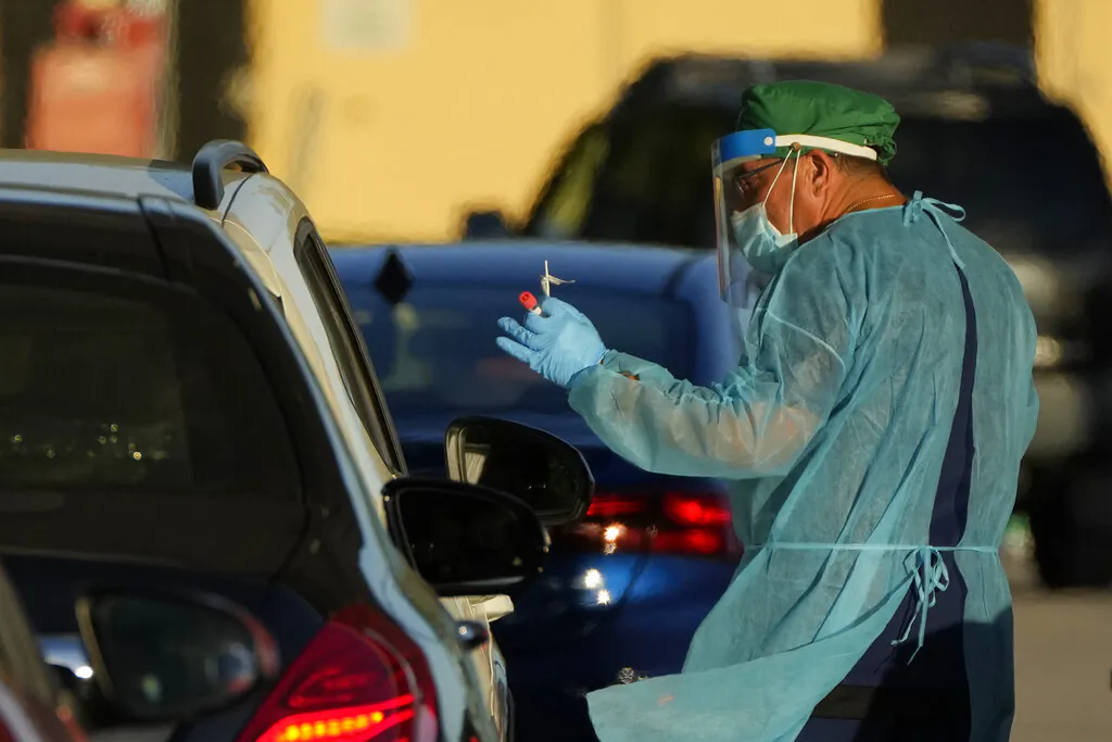 A health care worker tests people for COVID-19 at a drive-up testing center at Tropical Park in Miami, on Dec. 29, 2021. (Rebecca Blackwell/AP Photo)