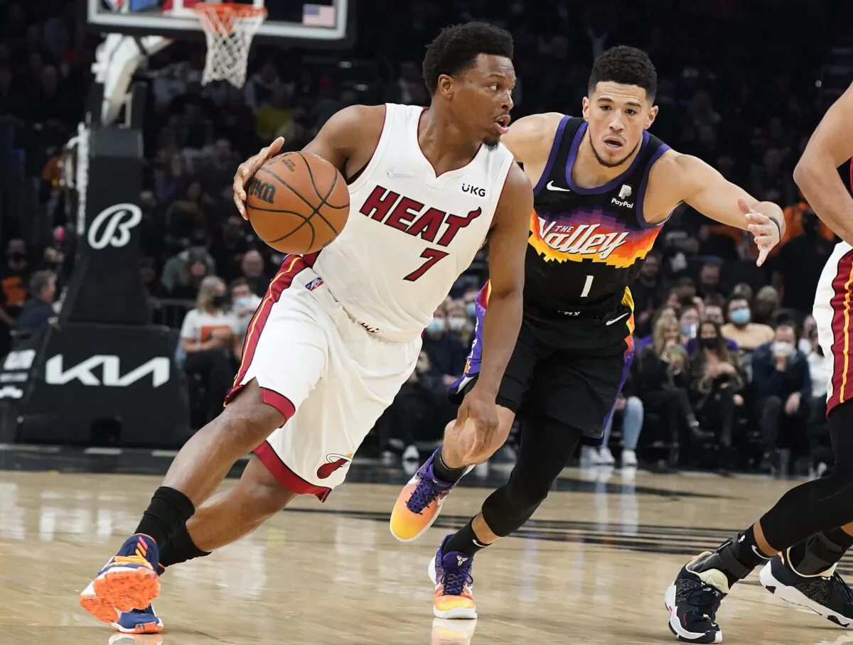 Miami Heat's Kyle Lowry (7) drives past Phoenix Suns' Devin Booker (1) during the first half of an NBA basketball game, in Phoenix, on Jan. 8, 2022. (Darryl Webb/AP Photo)