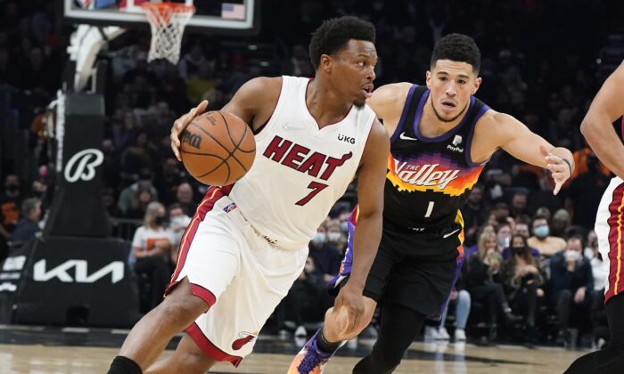 Miami Heat's Kyle Lowry (7) drives past Phoenix Suns' Devin Booker (1) during the first half of an NBA basketball game, in Phoenix, on Jan. 8, 2022. (Darryl Webb/AP Photo)