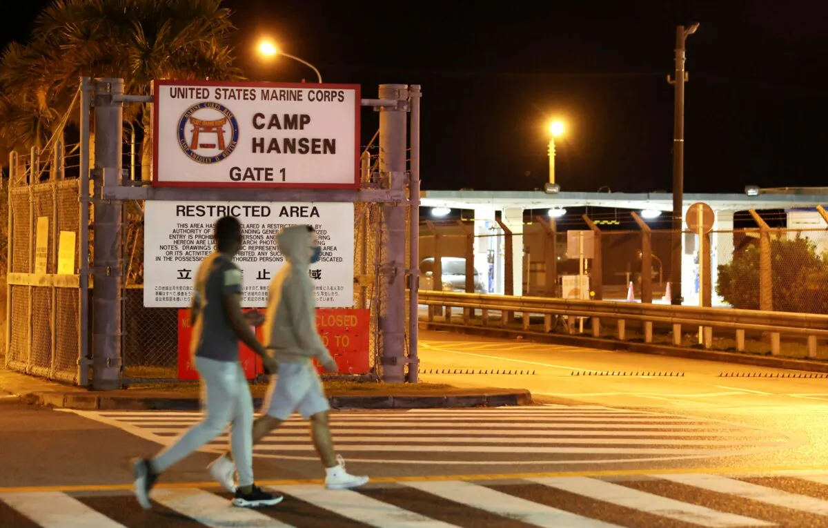 People walk past the gate of the U.S. Marine Corps' Camp Hansen, in Kin, Okinawa prefecture, southern Japan, on Jan. 6, 2022. (Kyodo News via AP)