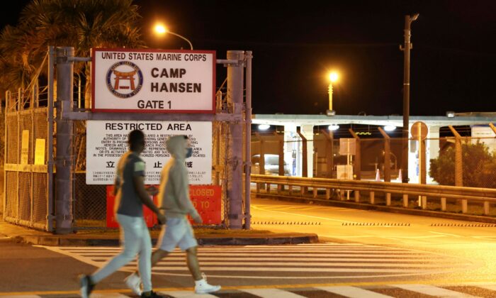 People walk past the gate of the U.S. Marine Corps' Camp Hansen, in Kin, Okinawa prefecture, southern Japan, on Jan. 6, 2022. (Kyodo News via AP)