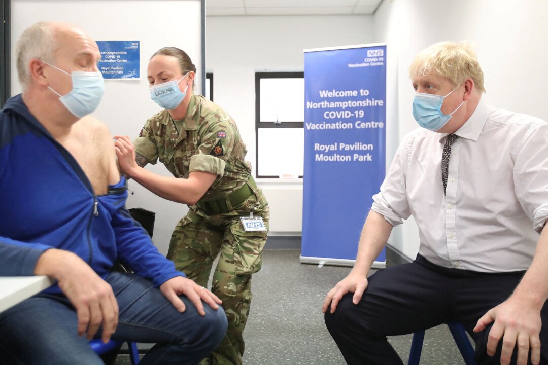 Britain's Prime Minister Boris Johnson (R) sits opposite Gordon Halfacre as he receives his COVID-19 vaccine from corporal Lorna MacDonald during a visit to a vaccination centre in Northampton on Jan. 6, 2022. (Peter Cziborra/Pool/AFP via Getty Images)