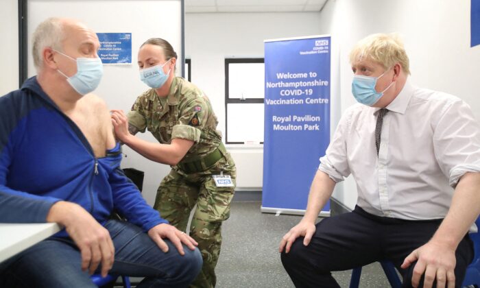 Britain's Prime Minister Boris Johnson (R) sits opposite Gordon Halfacre as he receives his COVID-19 vaccine from corporal Lorna MacDonald during a visit to a vaccination centre in Northampton on Jan. 6, 2022. (Peter Cziborra/Pool/AFP via Getty Images)