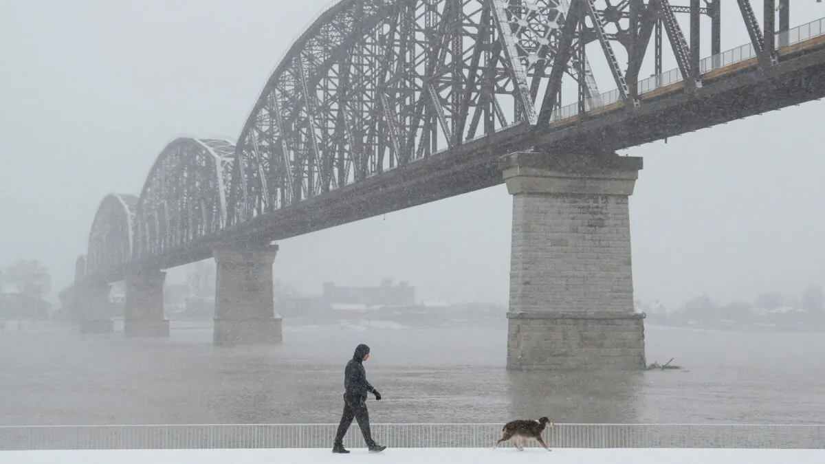 A man walks his dog by the Ohio River, during a snow storm in Louisville, Ky. on Jan. 6, 2022. (Amira Karaoud/Reuters)