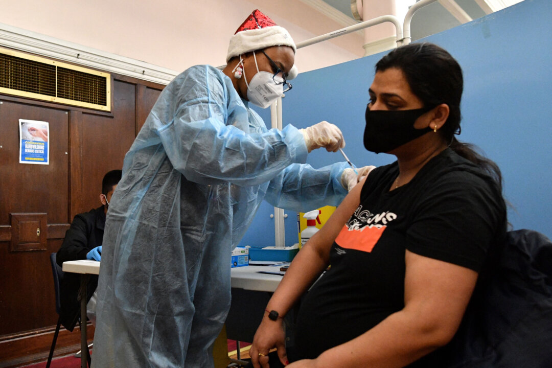 A health worker administers a dose of a COVID-19 vaccine to a pregnant woman at a pop-up vaccination centre at the Redbridge Town Hall, east London, on Dec. 25, 2021. (Justin Tallis/AFP via Getty Images)