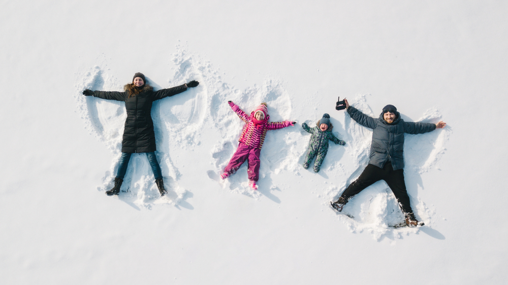 Family,Making,A,Snow,Angel.,Aerial,View.,Mother,And,Father